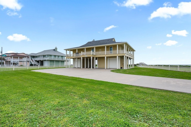 rear view of property featuring fence, driveway, an attached garage, and a lawn