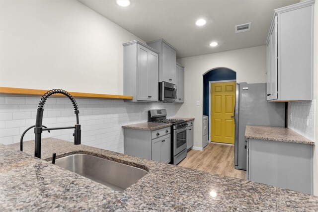 165 Camelot Place Ct, Conroe, TX 77304 - kitchen with appliances with stainless steel finishes, a sink, tasteful backsplash, gray cabinets, and light wood finished floors