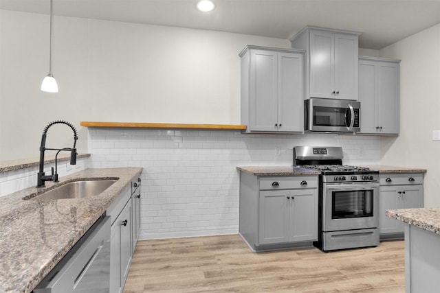 165 Camelot Place Ct, Conroe, TX 77304 - kitchen featuring appliances with stainless steel finishes, a sink, gray cabinets, light stone countertops, and recessed lighting