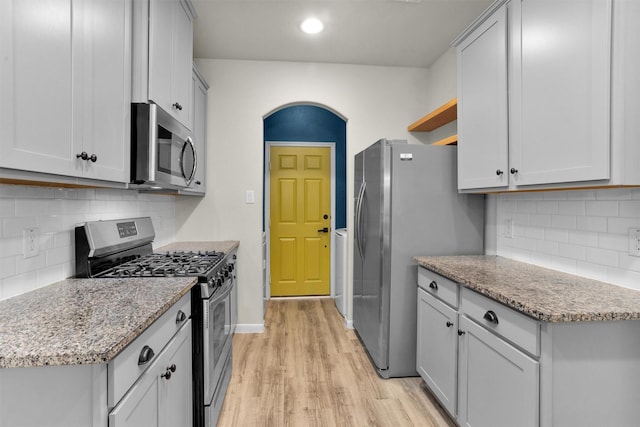 165 Camelot Place Ct, Conroe, TX 77304 - kitchen with appliances with stainless steel finishes, open shelves, light wood-style flooring, and tasteful backsplash