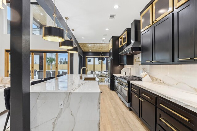 3902 Charleston St, Houston, TX 77021 - kitchen with double oven range, wall chimney range hood, light wood-style floors, light stone countertops, and decorative backsplash