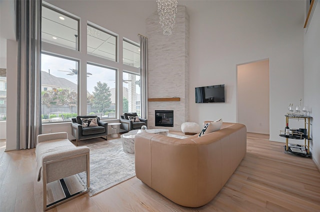 2611 Oakland Park Dr, Conroe, TX 77385 - living area featuring a towering ceiling, a stone fireplace, light wood-type flooring, and a chandelier
