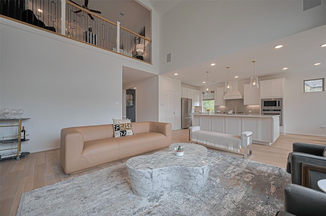 2611 Oakland Park Dr, Conroe, TX 77385 - living area with light wood-style flooring, baseboards, a towering ceiling, and recessed lighting