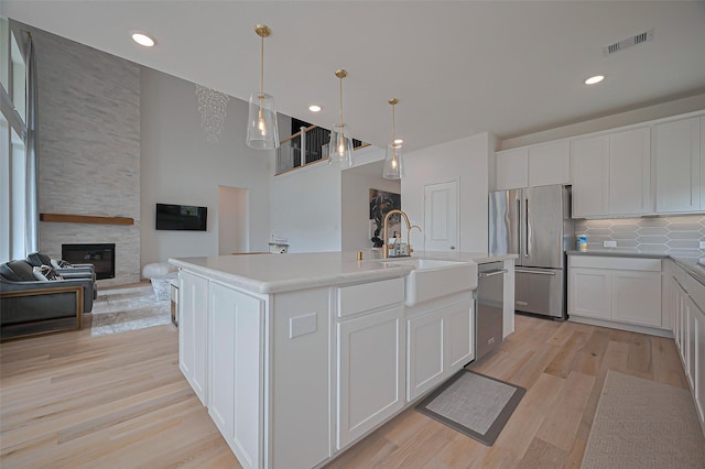2611 Oakland Park Dr, Conroe, TX 77385 - kitchen with stainless steel appliances, a sink, decorative backsplash, white cabinets, and light wood-style flooring