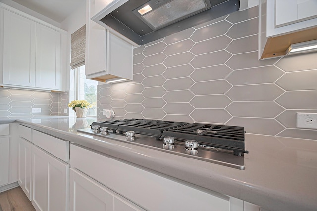 2611 Oakland Park Dr, Conroe, TX 77385 - kitchen featuring tasteful backsplash, stainless steel gas cooktop, wall chimney range hood, and white cabinets