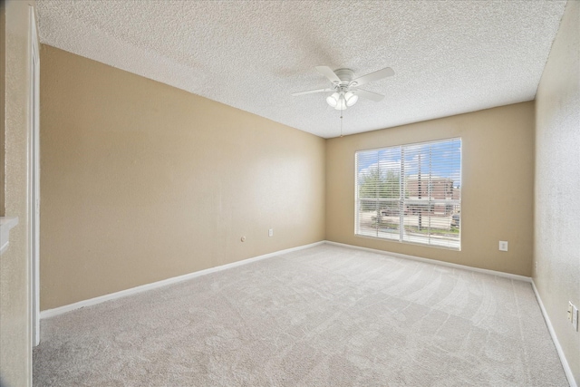 carpeted empty room featuring baseboards, ceiling fan, and a textured ceiling