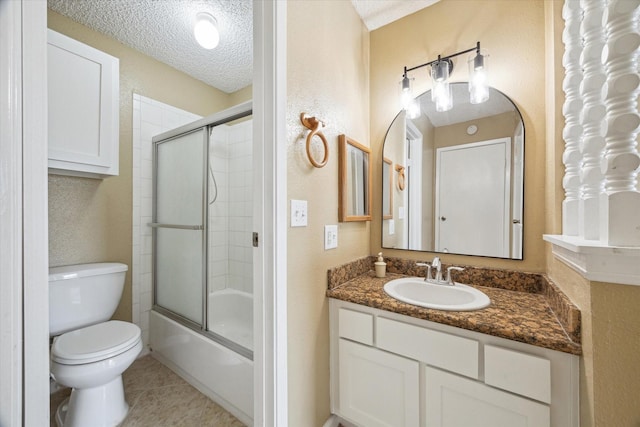bathroom with a textured ceiling, bath / shower combo with glass door, toilet, vanity, and tile patterned flooring