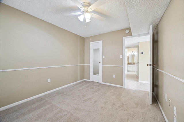 unfurnished bedroom featuring a ceiling fan, baseboards, light colored carpet, and a textured ceiling