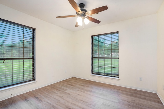unfurnished room with wood finished floors, a ceiling fan, and baseboards