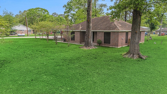 back of house with a yard, a shingled roof, and brick siding