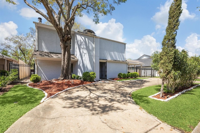view of front of home featuring stucco siding, fence, concrete driveway, and a front yard