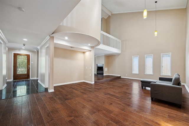 foyer entrance featuring hardwood / wood-style floors, a fireplace, baseboards, and crown molding