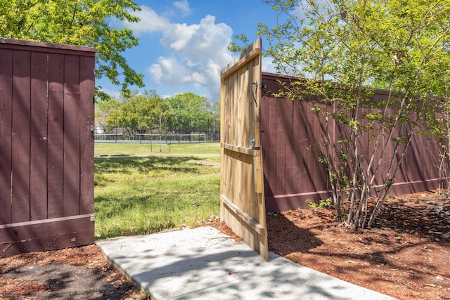 view of gate with a yard and fence