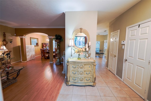 6019 Spanish Oak Dr, Pasadena, TX 77505 - hallway featuring ornate columns, arched walkways, light tile patterned flooring, crown molding, and baseboards