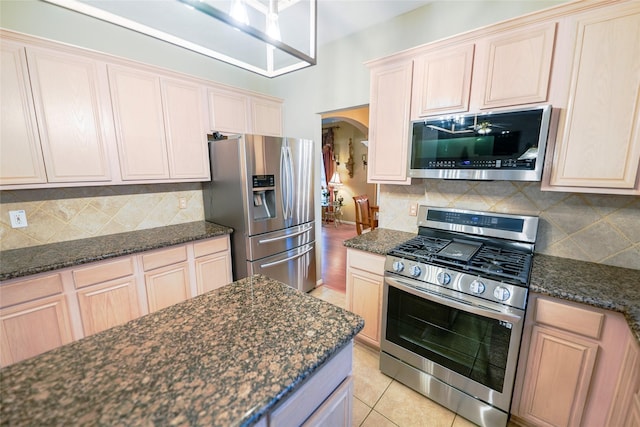 6019 Spanish Oak Dr, Pasadena, TX 77505 - kitchen featuring arched walkways, backsplash, appliances with stainless steel finishes, and dark stone counters