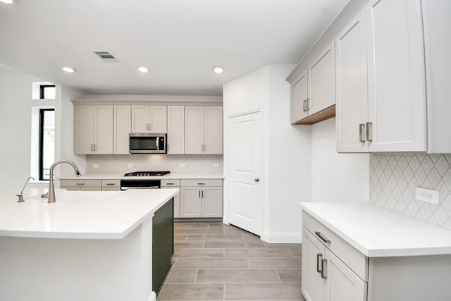 14647 Cedar Elm Ct, Willis, TX 77318 - kitchen with stainless steel microwave, backsplash, gas stovetop, light countertops, and recessed lighting