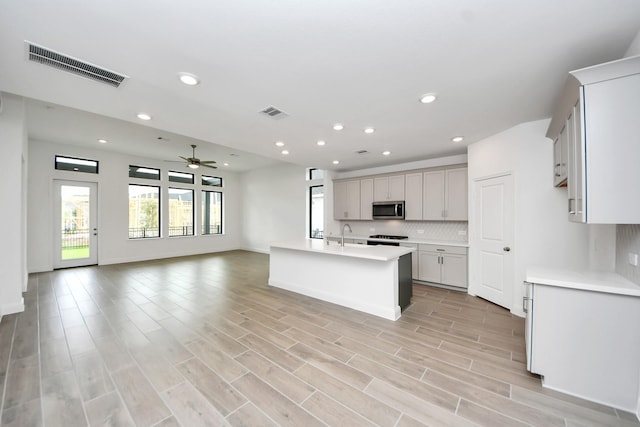 14647 Cedar Elm Ct, Willis, TX 77318 - kitchen with open floor plan, stainless steel microwave, ceiling fan, light countertops, and backsplash