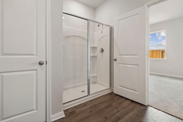 full bathroom featuring wood finished floors, baseboards, and a stall shower
