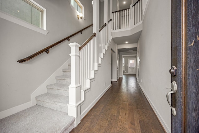 foyer featuring a towering ceiling, baseboards, stairs, and wood finished floors