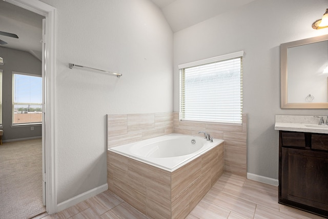full bathroom featuring baseboards, lofted ceiling, vanity, and a bath