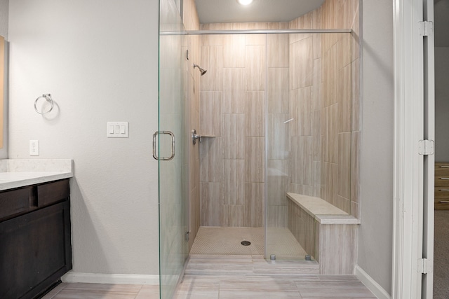 full bathroom featuring a stall shower, baseboards, and vanity