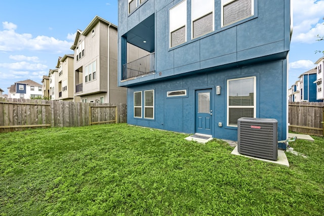 back of house with a lawn, cooling unit, stucco siding, and a fenced backyard