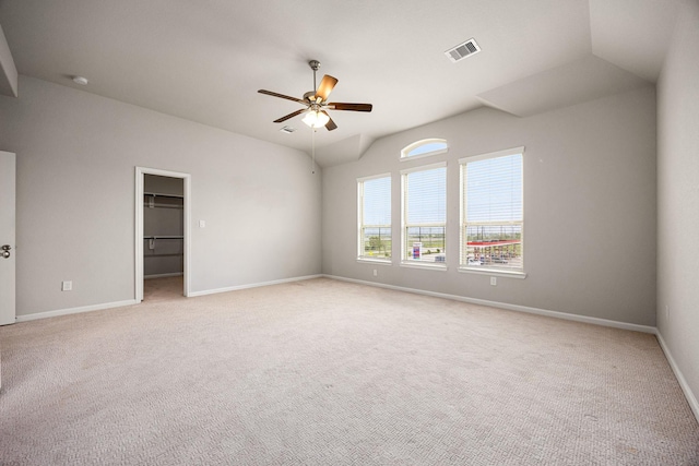 spare room with visible vents, baseboards, a ceiling fan, light carpet, and vaulted ceiling