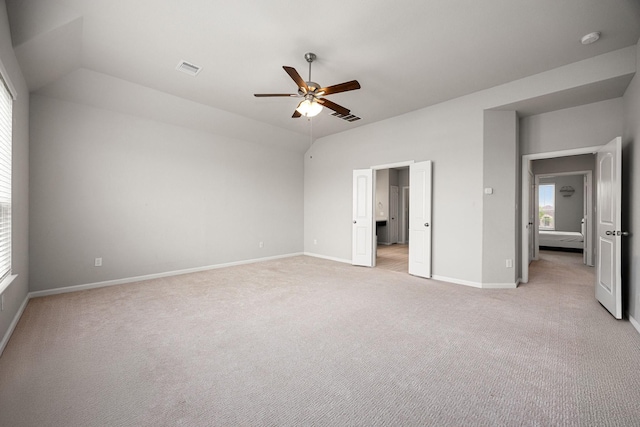unfurnished bedroom with baseboards, visible vents, vaulted ceiling, and light colored carpet