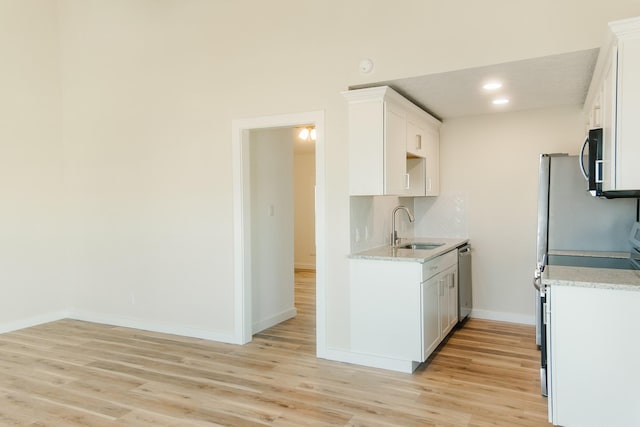 4406 Helen St, Hitchcock, TX 77563 - kitchen featuring baseboards, backsplash, a sink, light wood-style flooring, and appliances with stainless steel finishes