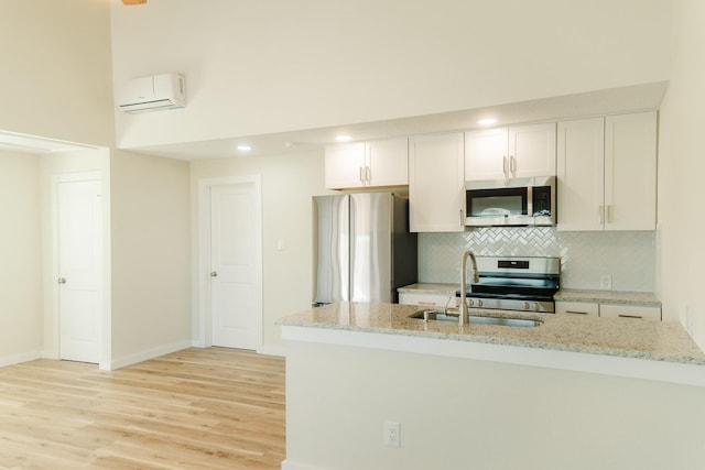 4406 Helen St, Hitchcock, TX 77563 - kitchen with light wood-type flooring, decorative backsplash, a sink, appliances with stainless steel finishes, and a wall mounted air conditioner