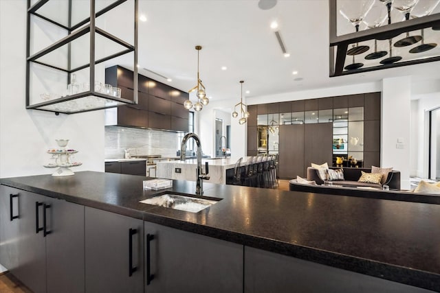 3835 Olympia Dr, Houston, TX 77019 - kitchen featuring a sink, modern cabinets, tasteful backsplash, pendant lighting, and dark brown cabinets