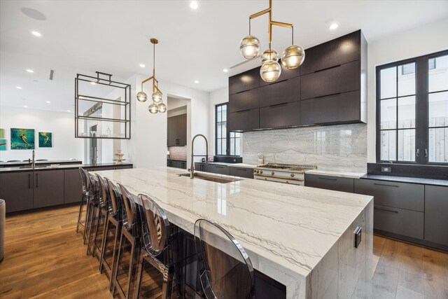 3835 Olympia Dr, Houston, TX 77019 - kitchen with modern cabinets, a sink, light stone counters, tasteful backsplash, and a large island with sink