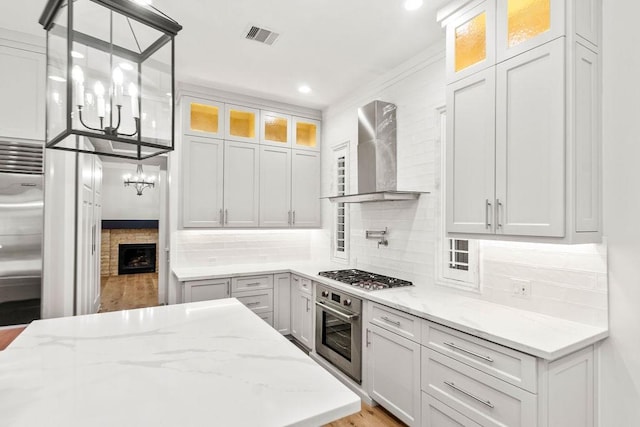 1024 Waverly St, Houston, TX 77008 - kitchen with wall chimney range hood, a chandelier, stainless steel appliances, light stone counters, and backsplash