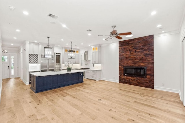 1024 Waverly St, Houston, TX 77008 - kitchen featuring built in fridge, wall chimney exhaust hood, crown molding, light countertops, and a fireplace