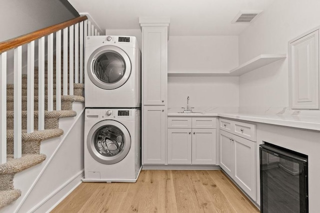 1024 Waverly St, Houston, TX 77008 - clothes washing area with stacked washer / drying machine, wine cooler, light wood-style flooring, cabinet space, and wet bar