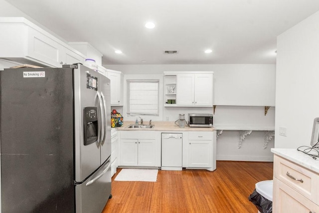 1024 Waverly St, Houston, TX 77008 - kitchen with stainless steel appliances, open shelves, light wood-type flooring, a sink, and white cabinets
