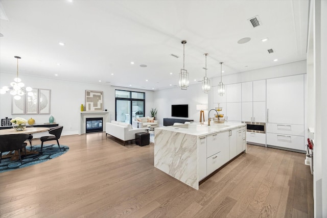 kitchen featuring modern cabinets, light wood-style flooring, white cabinetry, visible vents, and a sink