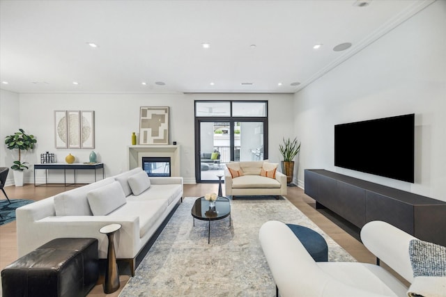living area featuring crown molding, baseboards, and light wood finished floors