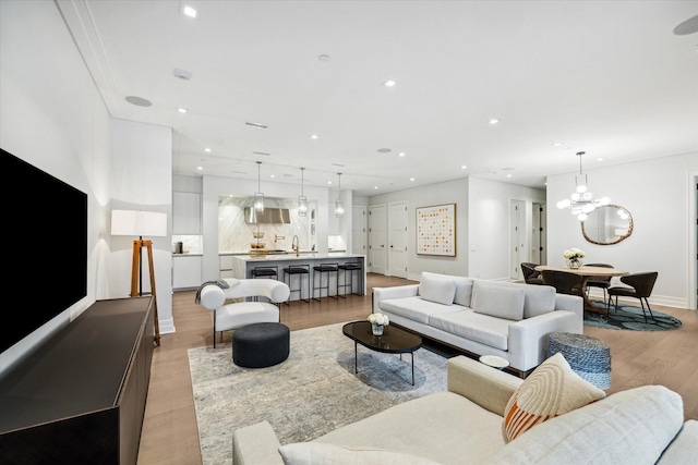 living area featuring light wood-style flooring, recessed lighting, a chandelier, and baseboards
