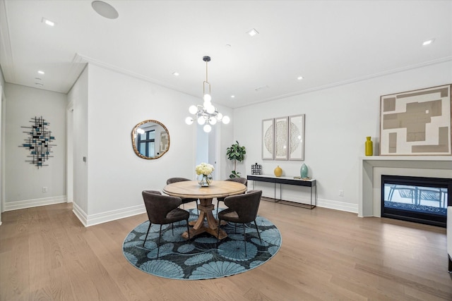 dining area with an inviting chandelier, a glass covered fireplace, recessed lighting, wood finished floors, and baseboards