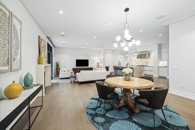 dining space featuring a chandelier, light wood-style floors, baseboards, and recessed lighting