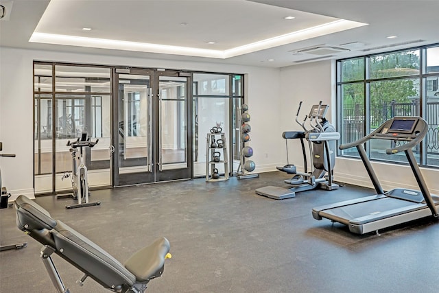 workout area with french doors, baseboards, and a raised ceiling