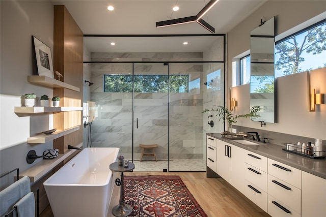 bathroom featuring vanity, a freestanding tub, a stall shower, and wood finished floors