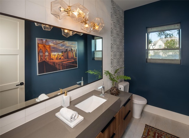bathroom with toilet, an inviting chandelier, and vanity