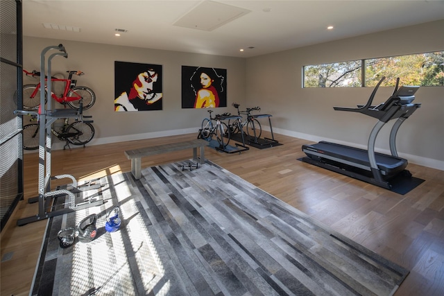 exercise room with baseboards, visible vents, and wood finished floors