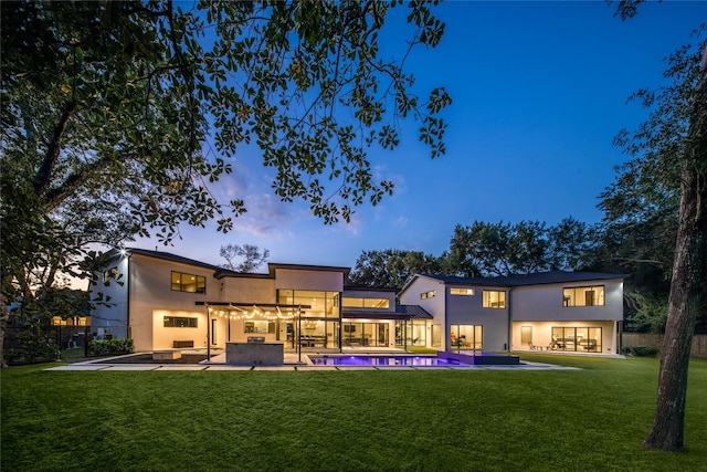 back of house featuring a lawn, a patio, stucco siding, and an outdoor pool