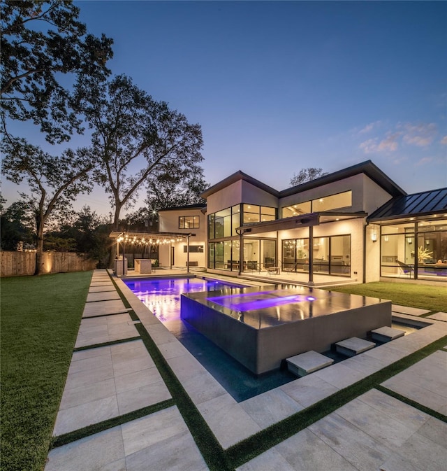 pool featuring a yard, a patio, an in ground hot tub, and fence