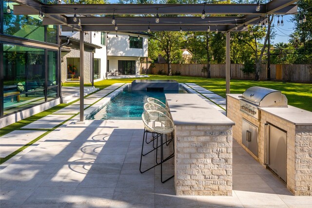 view of swimming pool featuring fence, grilling area, exterior kitchen, and a bar