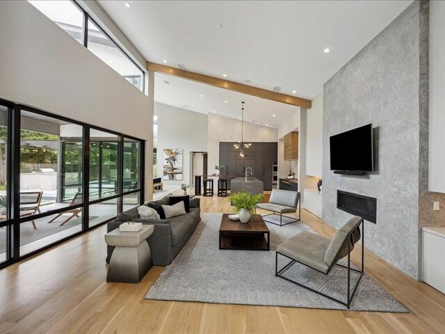 living room with plenty of natural light, light wood-type flooring, high vaulted ceiling, and a large fireplace