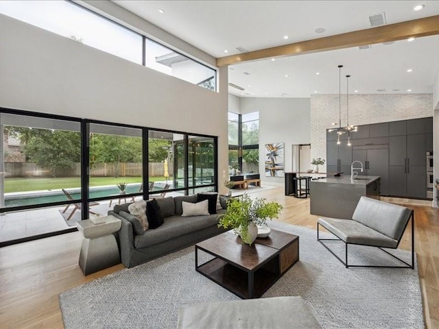 living room featuring visible vents, recessed lighting, light wood-style flooring, and a towering ceiling